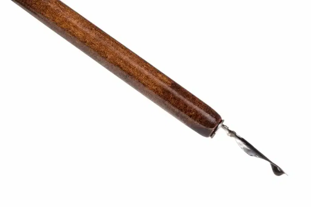 black ink drop on tip of nib of brown dip pen