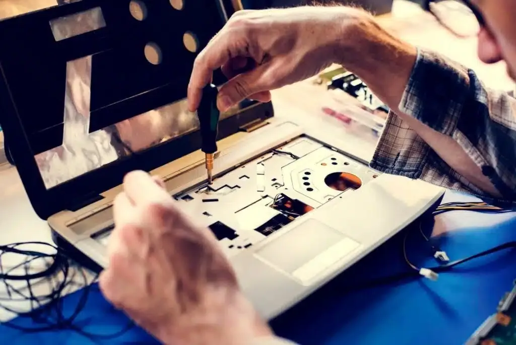 Closeup of hands with screwdriver working on computer laptop