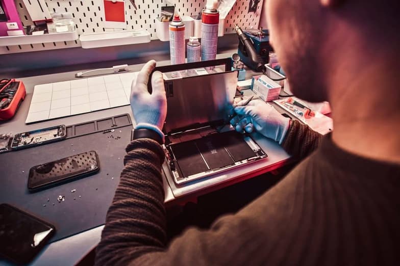 The technician repairs a broken tablet computer in a repair shop